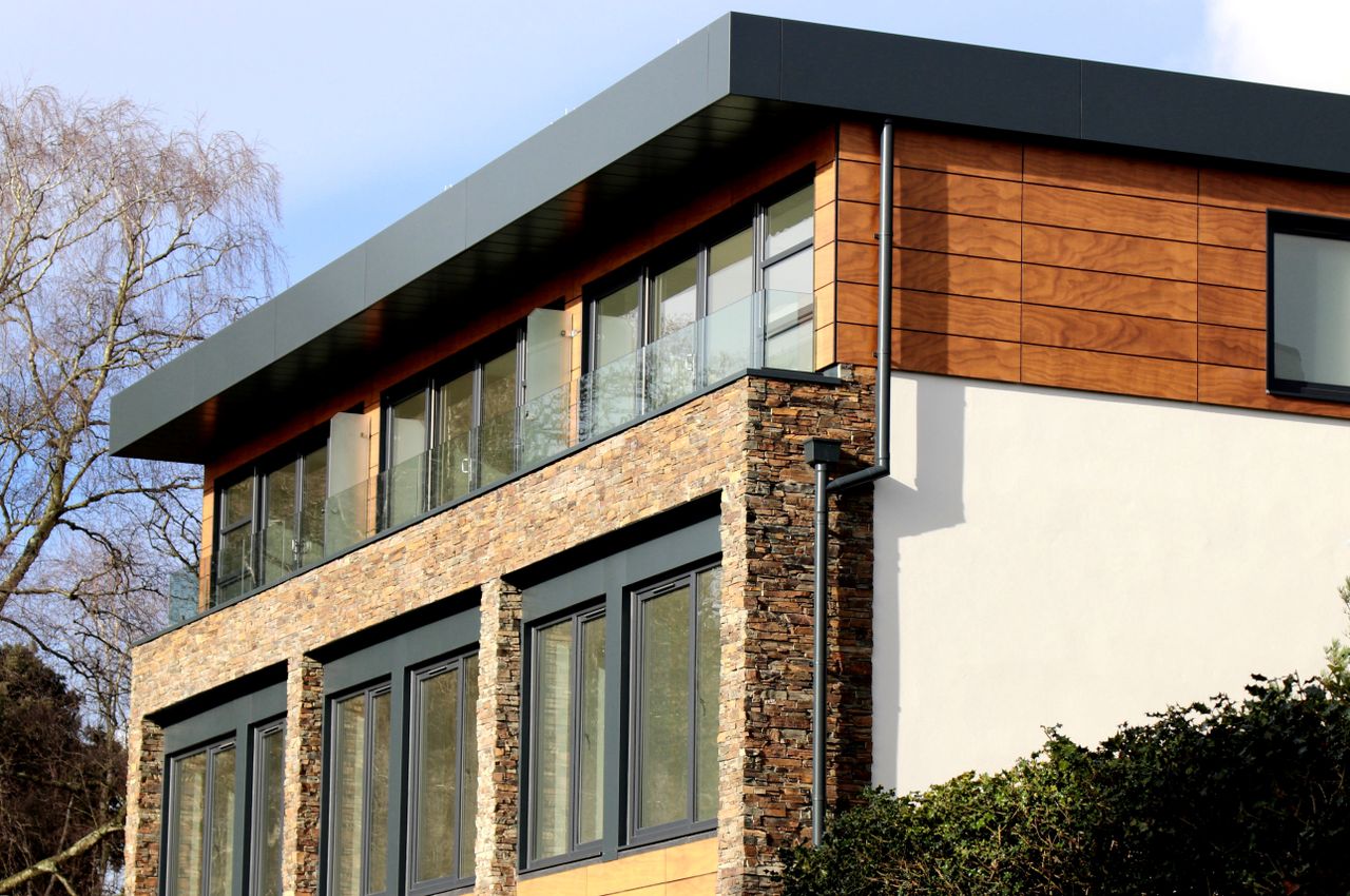 mission-img Contemporary house in Poole featuring a striking mix of stone and wood facade with large windows.