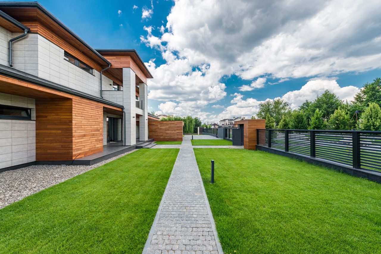 about-01 Scenery green yard of modern residential house with trees outside fence under blue cloudy sky