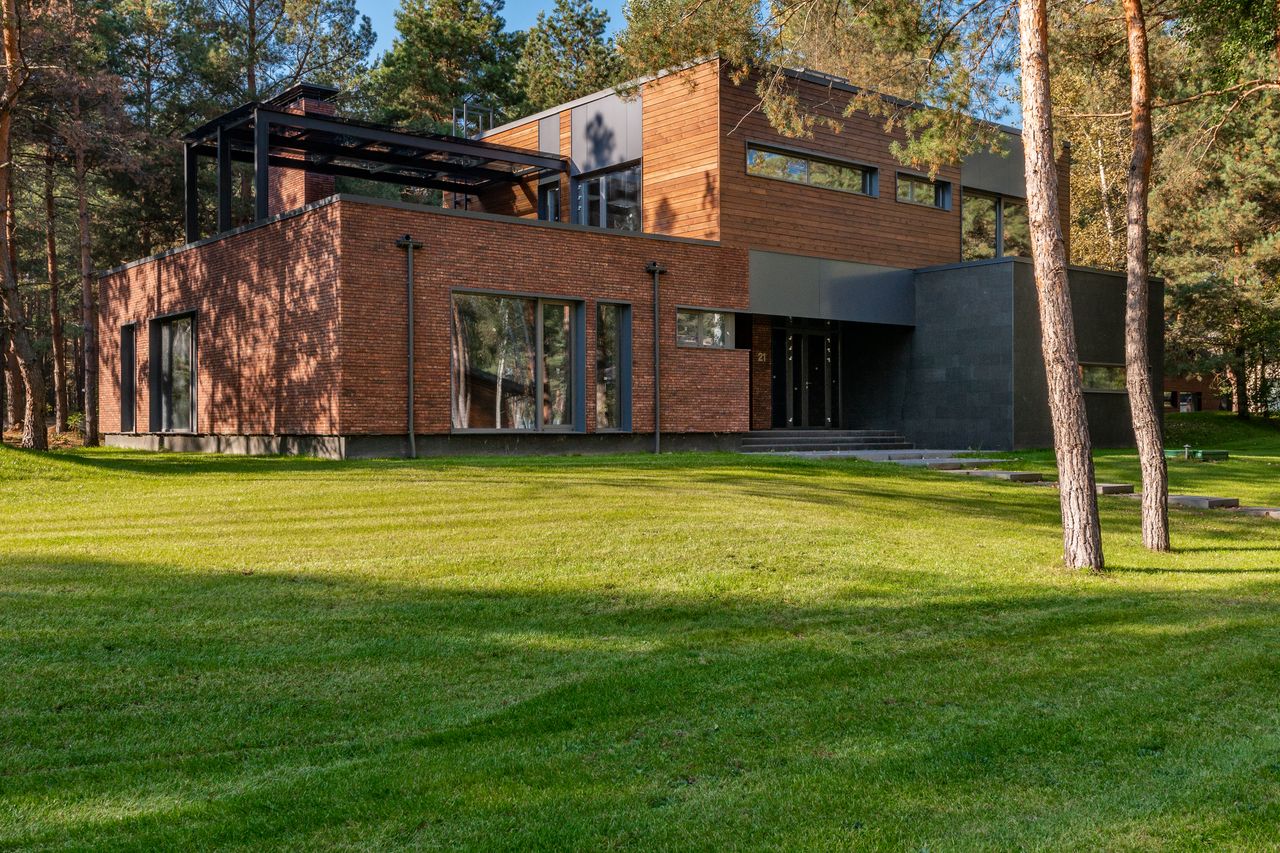 home-hero-bg Contemporary house with large windows surrounded by lush greenery and trees.